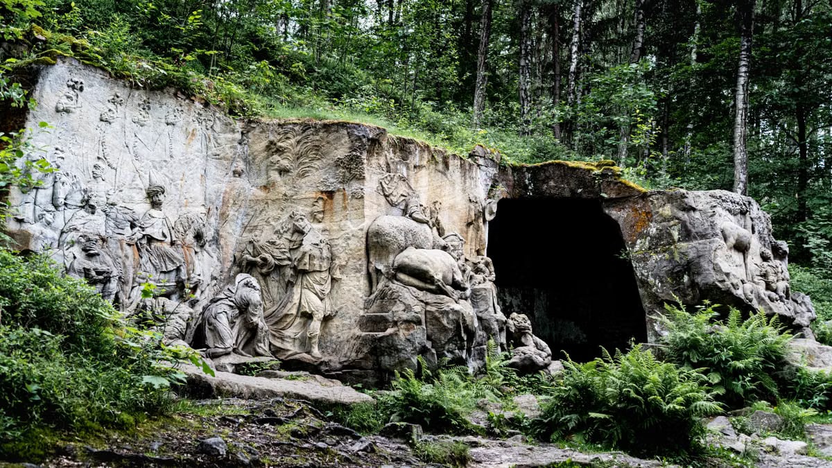 Detailed view of sculpted rock carvings amidst a lush, green forest landscape.